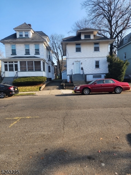 a front view of residential houses with cars parked on road