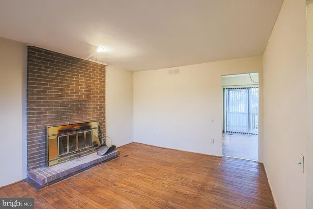 a view of empty room with wooden floor and fireplace