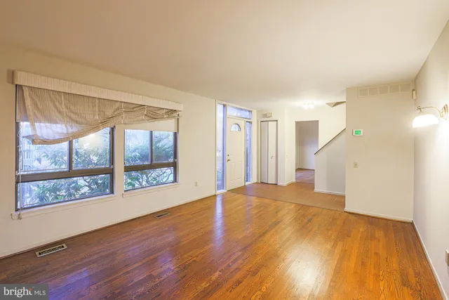 a view of an empty room with wooden floor and a window