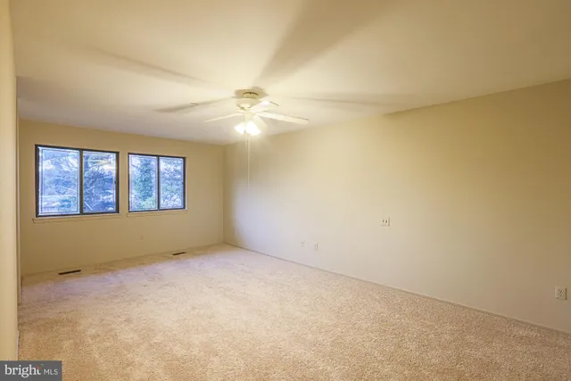 an empty room with windows and chandelier fan