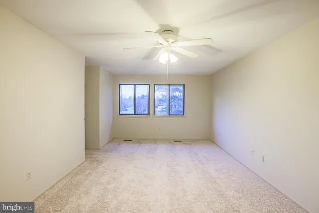 an empty room with windows and fan
