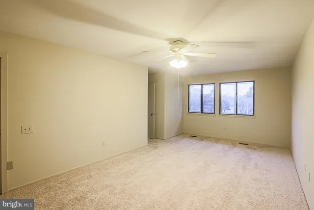 an empty room with windows and fan