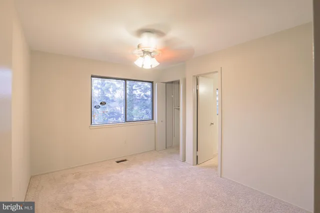 an empty room with windows and chandelier fan