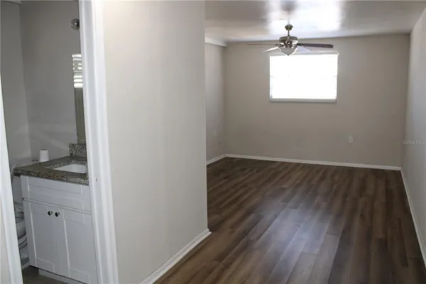 a view of a hallway with wooden floor and a bathroom