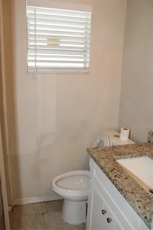 a bathroom with a granite countertop toilet sink and window