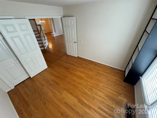 a view of an empty room with wooden floor and stairs