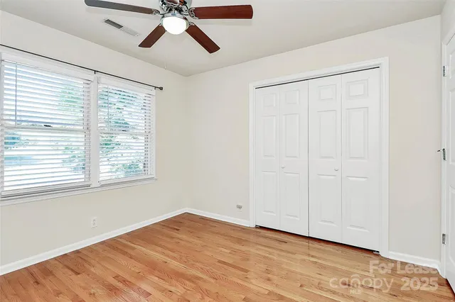 a view of empty room with wooden floor and fan