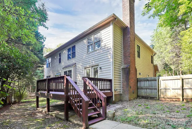 a view of a house with a wooden deck and a trees