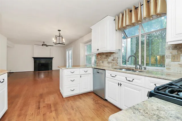 a kitchen with stainless steel appliances a stove a sink dishwasher and a fireplace with wooden floor