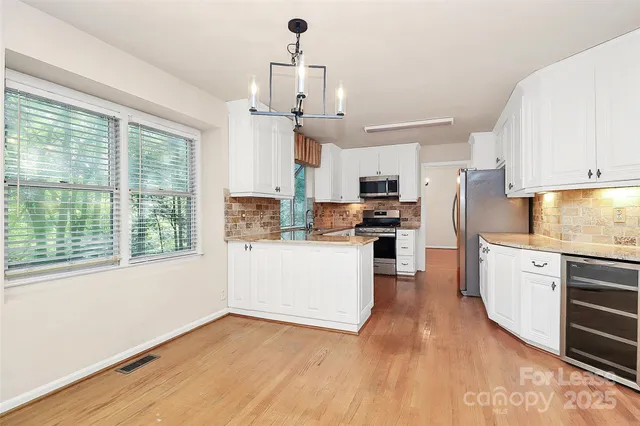 a kitchen with stainless steel appliances granite countertop a stove a refrigerator a sink dishwasher and a fireplace with wooden floor