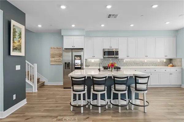a kitchen with stainless steel appliances kitchen island granite countertop a dining table chairs and refrigerator