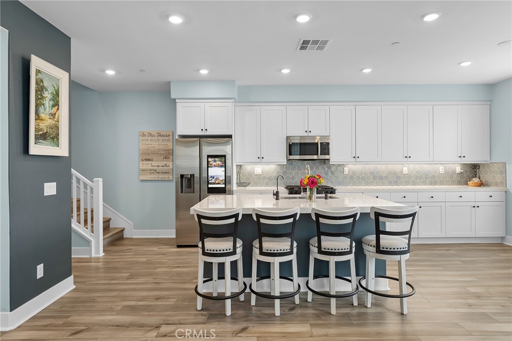 705 Arrowleaf Road Rancho Mission Viejo, CA 92694 - Photo 3 of 48 a kitchen with stainless steel appliances kitchen island granite countertop a dining table chairs and refrigerator