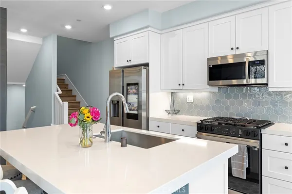 a kitchen with stainless steel appliances a stove a sink a microwave a refrigerator and cabinets