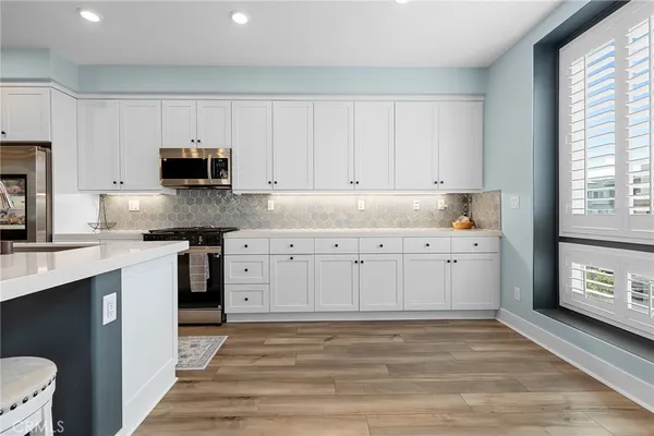 a kitchen with stainless steel appliances a white stove top oven and white cabinets