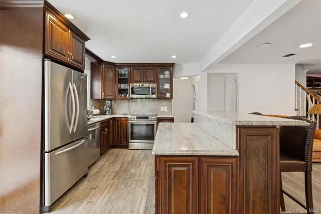 a kitchen with stainless steel appliances granite countertop a refrigerator a stove and a sink with wooden floors