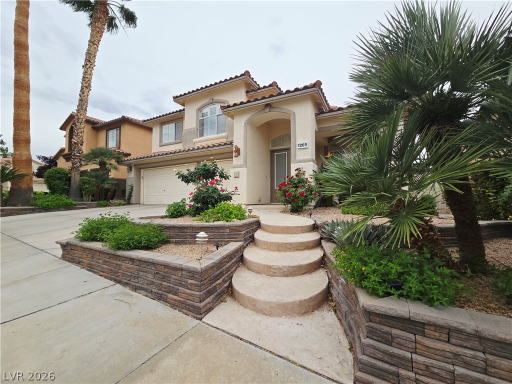 Mediterranean / spanish house with stucco siding, a tiled roof, concrete driveway, and a garage
