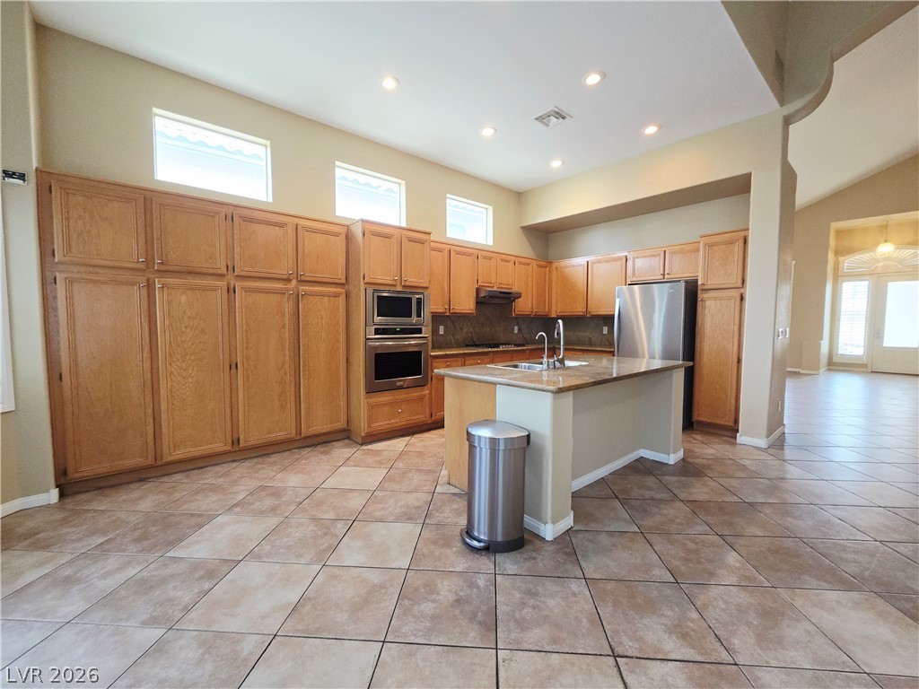 1265 Moon Vision Street Henderson, NV 89052 - Photo 11 of 35 Kitchen featuring light tile patterned floors, stainless steel appliances, backsplash, an island with sink, and recessed lighting