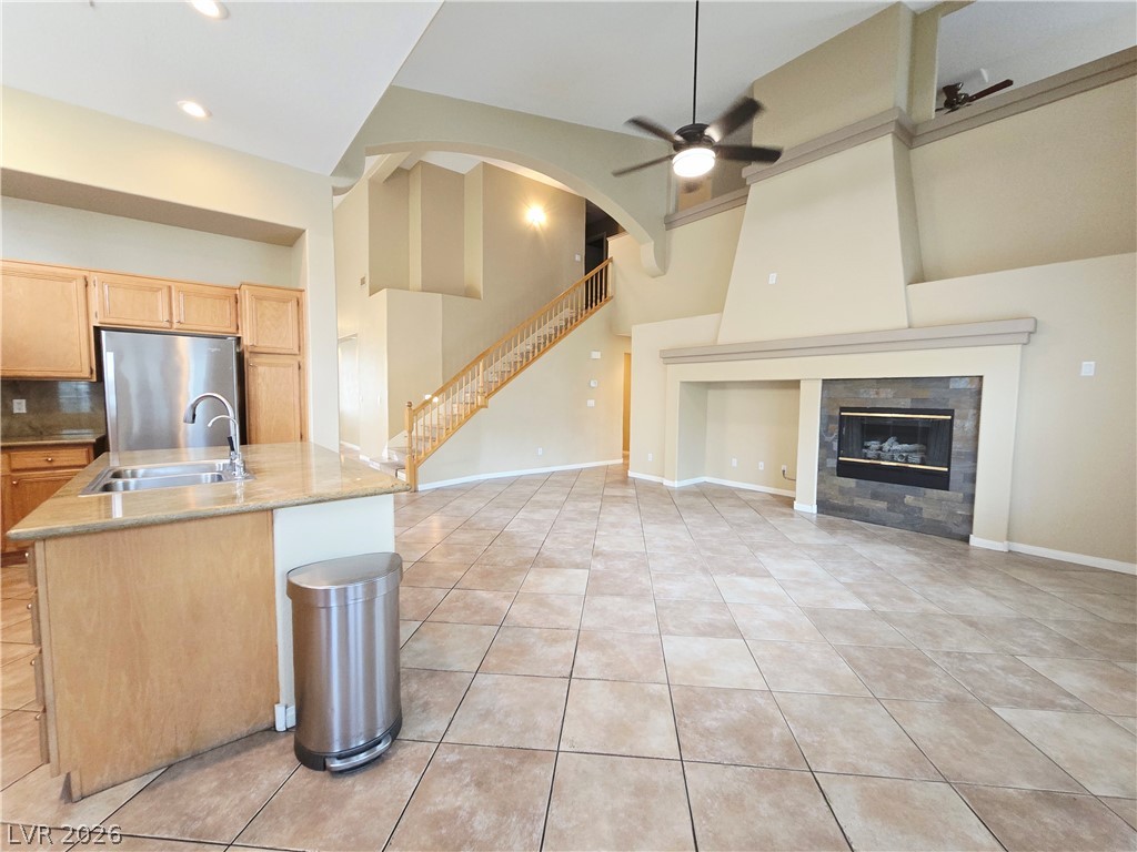 1265 Moon Vision Street Henderson, NV 89052 - Photo 12 of 35 Kitchen with a ceiling fan, light wood finish cabinets, freestanding refrigerator, a kitchen island with sink, and a tiled fireplace