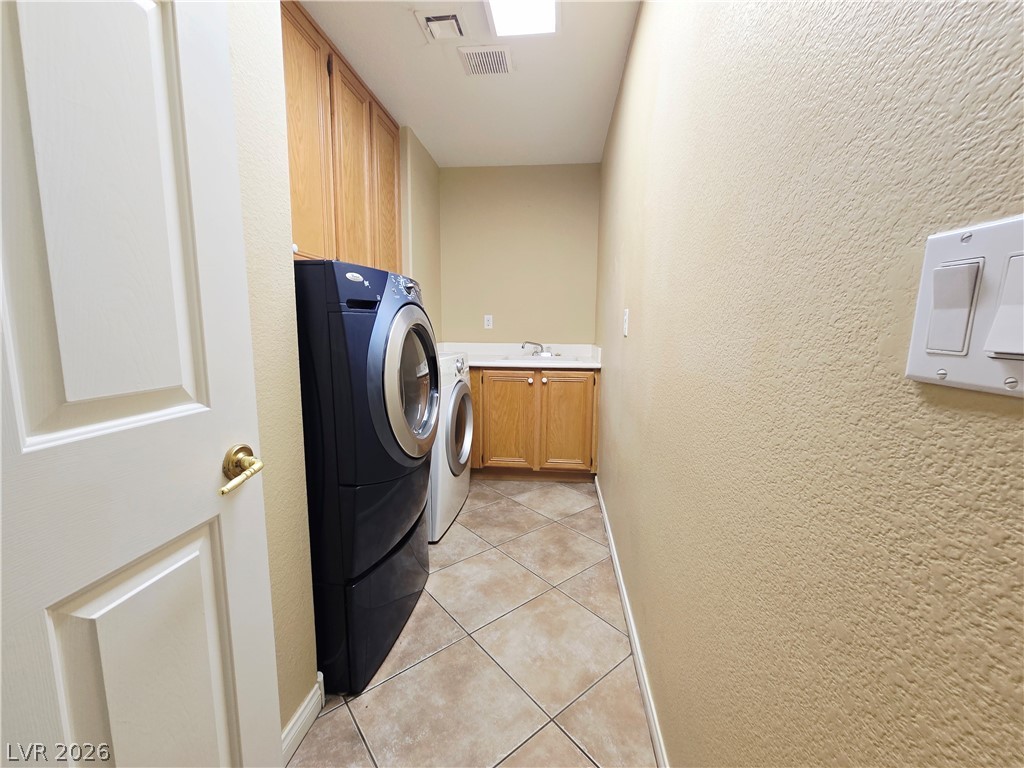 1265 Moon Vision Street Henderson, NV 89052 - Photo 18 of 35 Laundry room featuring a textured wall, washer and clothes dryer, cabinet space, and light tile patterned floors