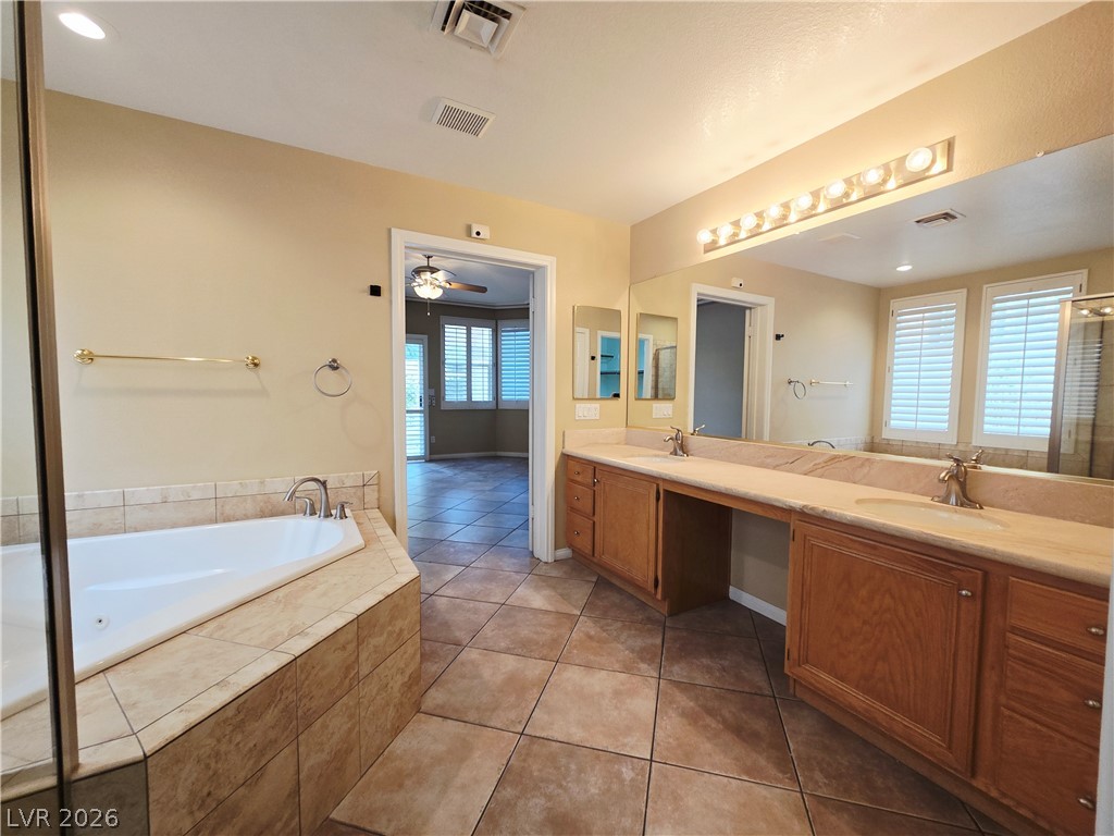 1265 Moon Vision Street Henderson, NV 89052 - Photo 23 of 35 Full bathroom featuring a tub with jets, double vanity, light tile patterned floors, a ceiling fan, and recessed lighting