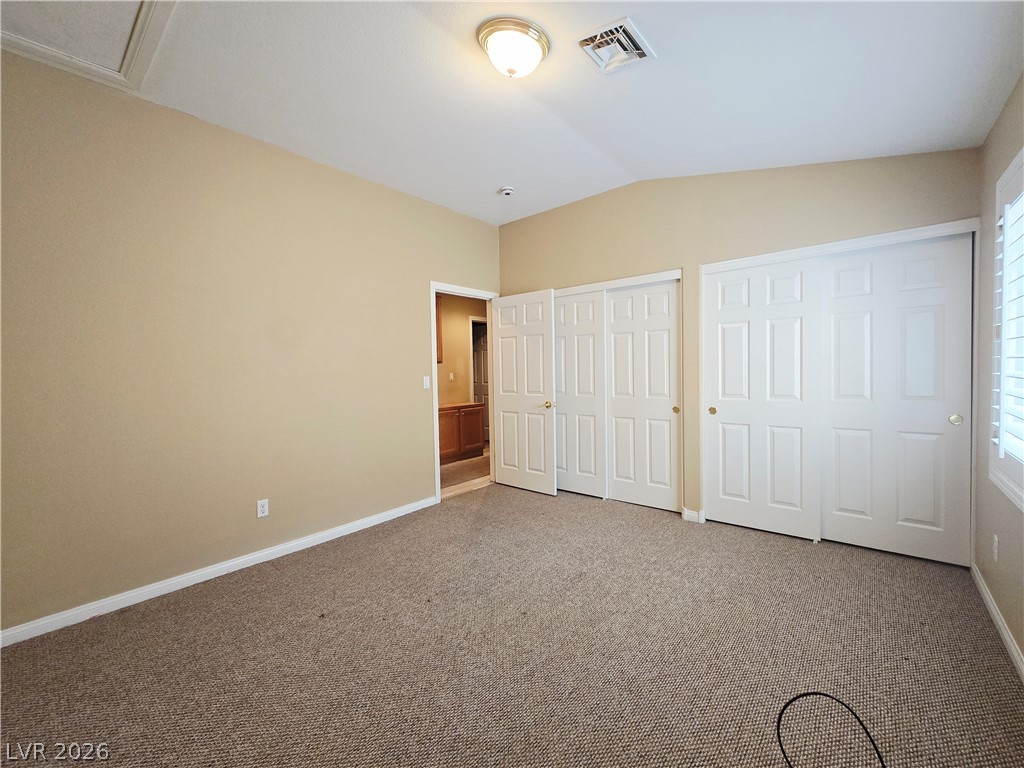 1265 Moon Vision Street Henderson, NV 89052 - Photo 27 of 35 Unfurnished bedroom featuring two closets, carpet floors, and lofted ceiling