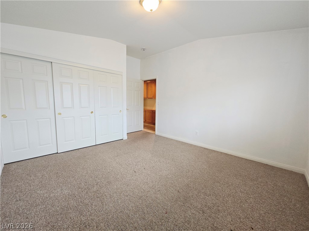 1265 Moon Vision Street Henderson, NV 89052 - Photo 29 of 35 Unfurnished bedroom with a closet, vaulted ceiling, and carpet floors
