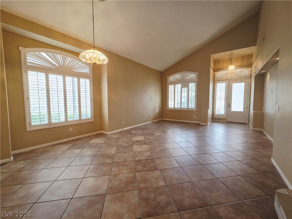 1265 Moon Vision Street Henderson, NV 89052 - Photo 6 of 35 Empty room with lofted ceiling, hanging lights, and light tile patterned floors