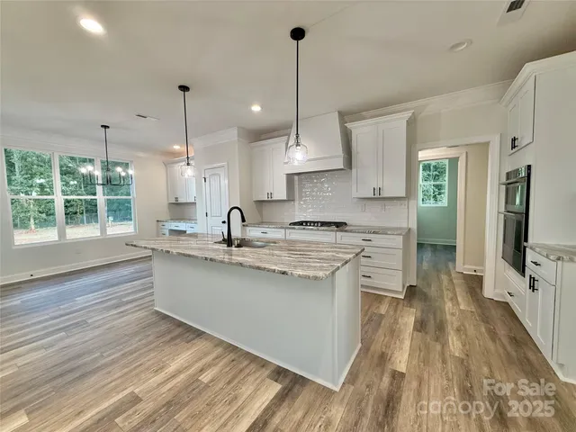 a kitchen with stainless steel appliances granite countertop a sink a stove and a wooden floors