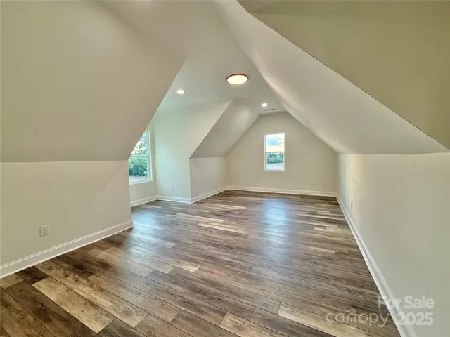 an empty room with wooden floor ceiling fan and windows