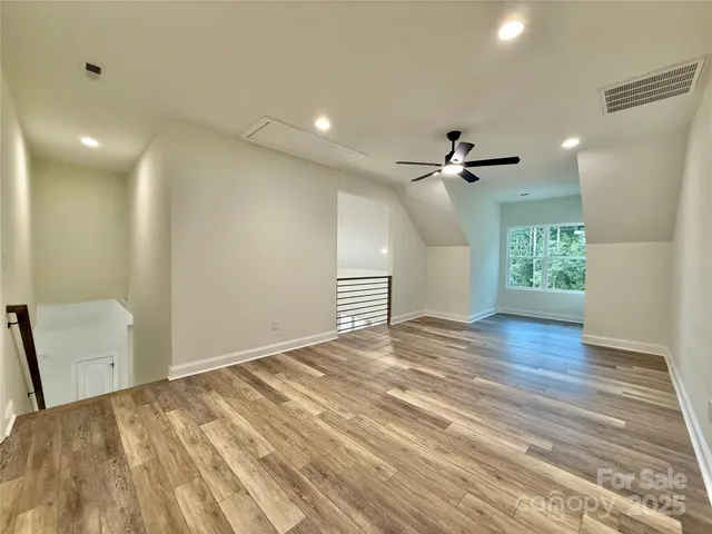 an empty room with wooden floor ceiling fan and windows