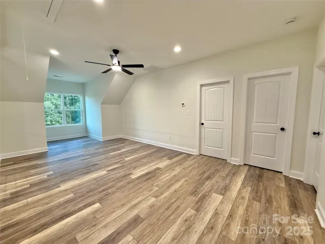 a view of empty room with wooden floor and fan