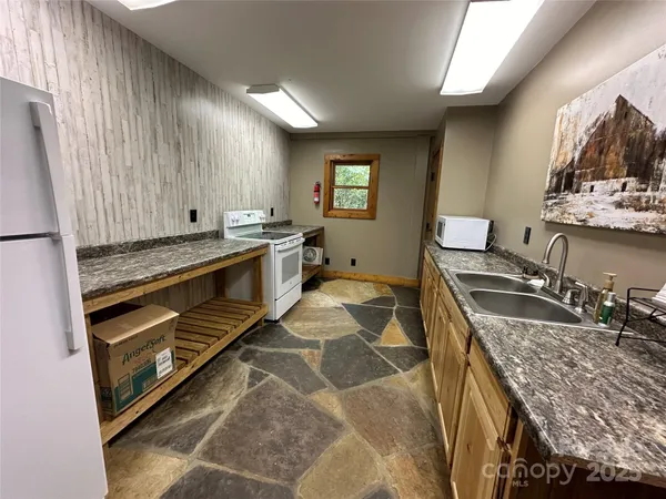 a kitchen with kitchen island granite countertop a sink stove and cabinets