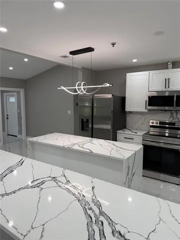 a kitchen with stainless steel appliances kitchen island granite countertop a sink and a stove