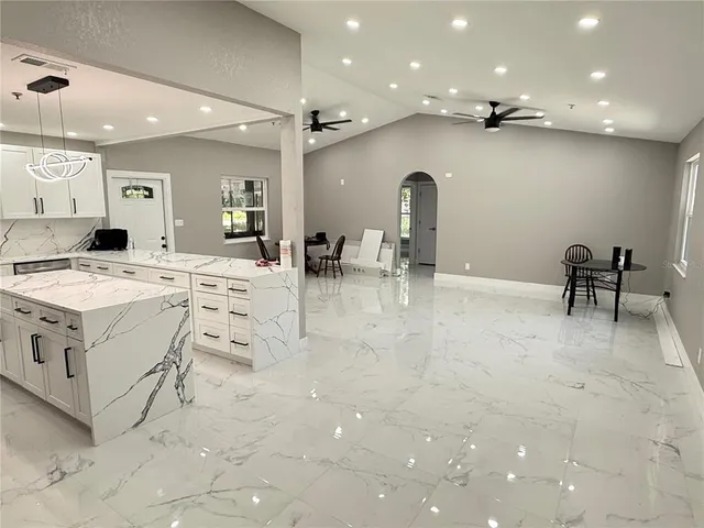 a large white kitchen with a stove a table and chair