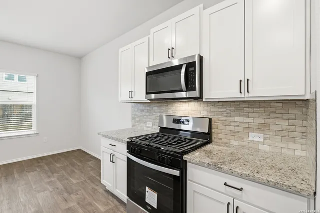 a kitchen with stainless steel appliances granite countertop white cabinets and a stove top oven