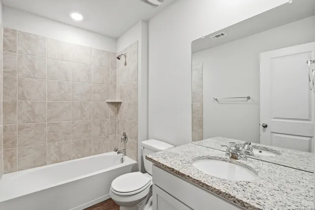 a bathroom with a granite countertop sink toilet tub and shower