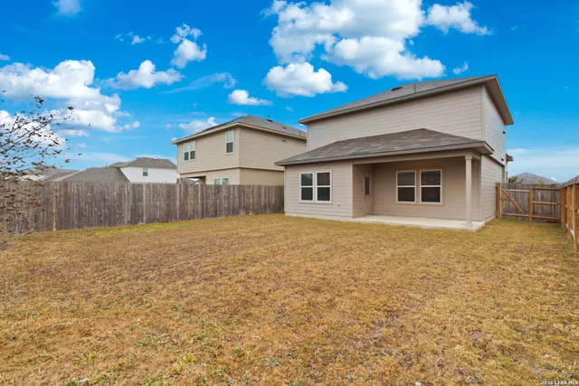 a view of a house with backyard and wooden fence