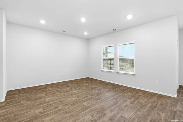 an empty room with wooden floor and windows