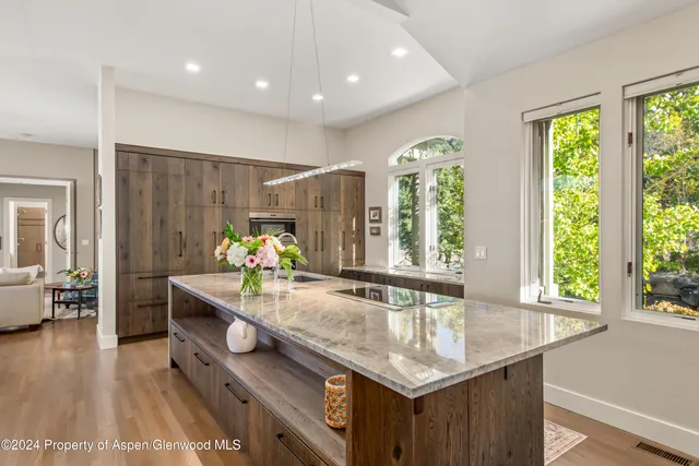 a dining hall with stainless steel appliances granite countertop a sink dishwasher and a dining table with wooden floor