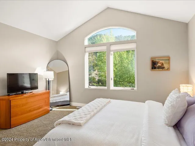 a bedroom with a bed and a flat tv screen on dresser