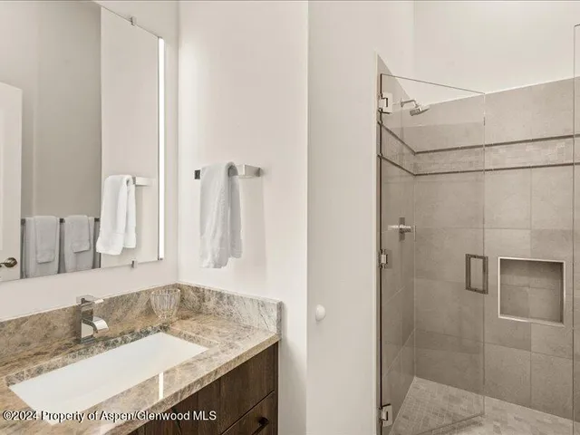 a bathroom with a granite countertop sink a mirror and shower