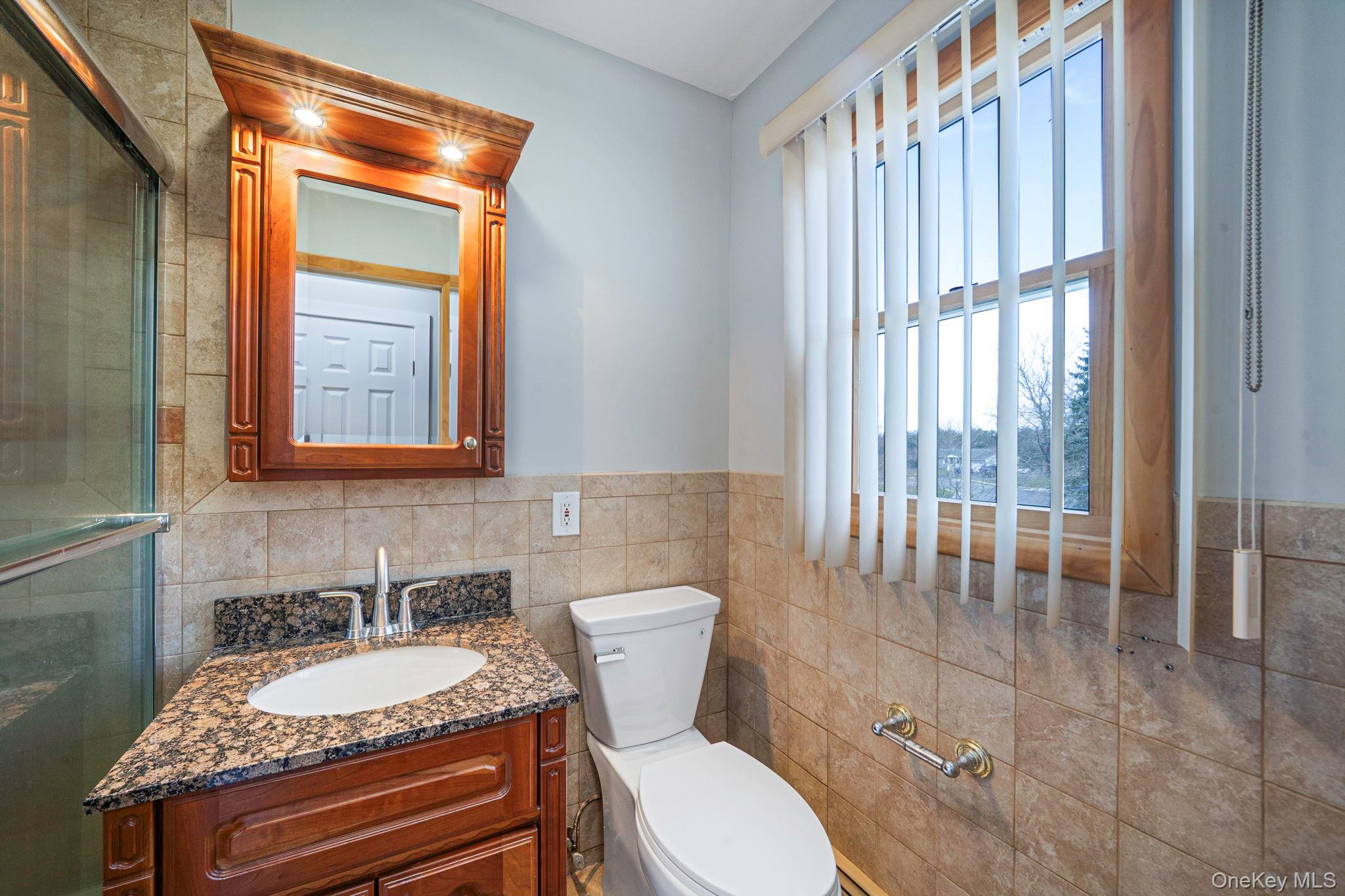 71 Loop Drive Sayville, NY 11782 - Photo 23 of 45 a bathroom with a granite countertop sink mirror vanity and toilet
