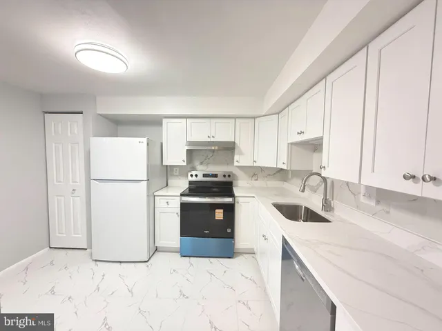 a kitchen with a sink a refrigerator and a stove top oven