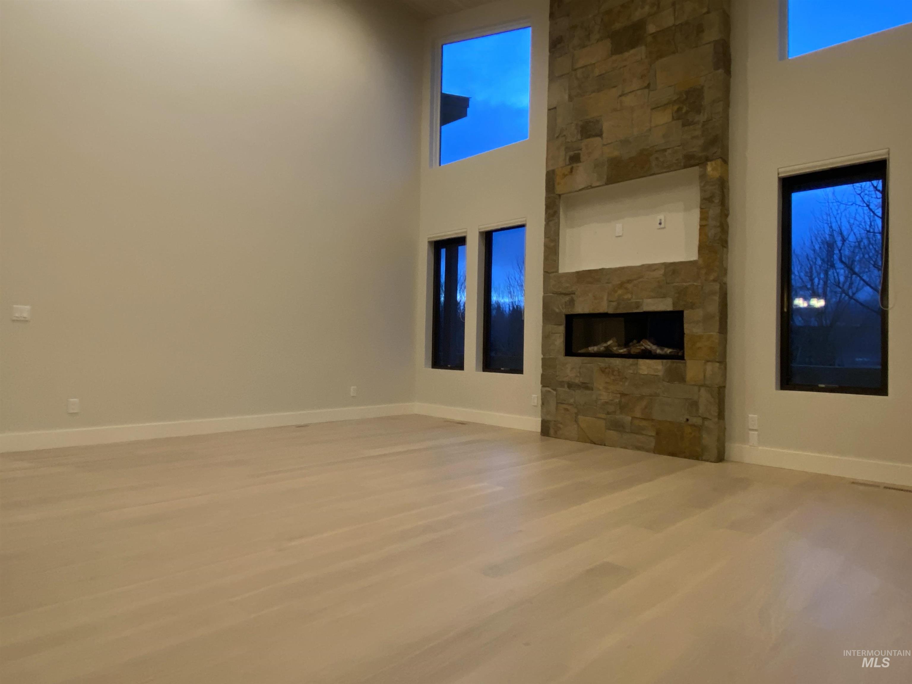 27 Streamside Drive Hailey, ID 83333 - Photo 3 of 39 Unfurnished living room with a high ceiling, a fireplace, and light wood-style floors