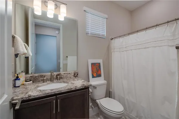 a bathroom with a granite countertop sink toilet and a mirror