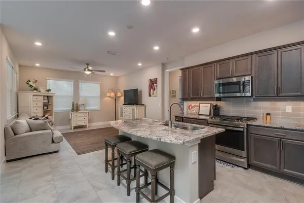 a kitchen with stainless steel appliances granite countertop a stove top oven a sink dishwasher a dining table and chairs