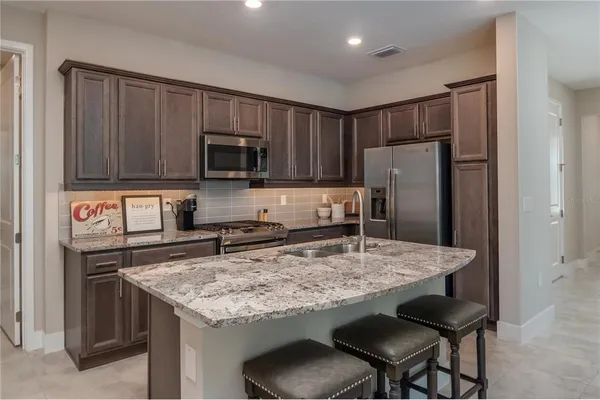 a kitchen with stainless steel appliances granite countertop a stove refrigerator sink and microwave