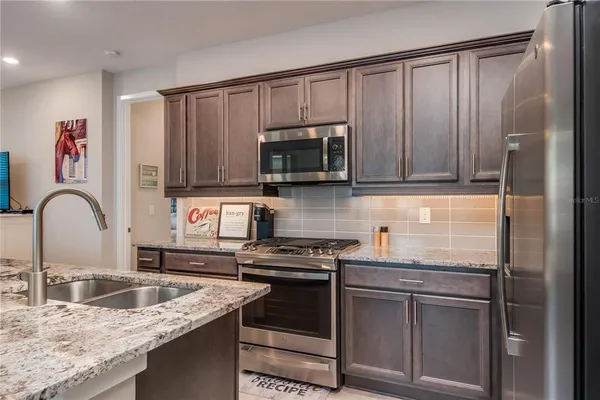 a kitchen with stainless steel appliances granite countertop a stove a sink and a microwave