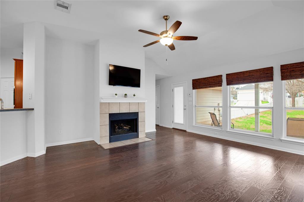 281 Hutton Kyle, TX 78640 - Photo 7 of 37 Natural light streams into this welcoming living area, showcasing rich wood flooring and a cozy fireplace.