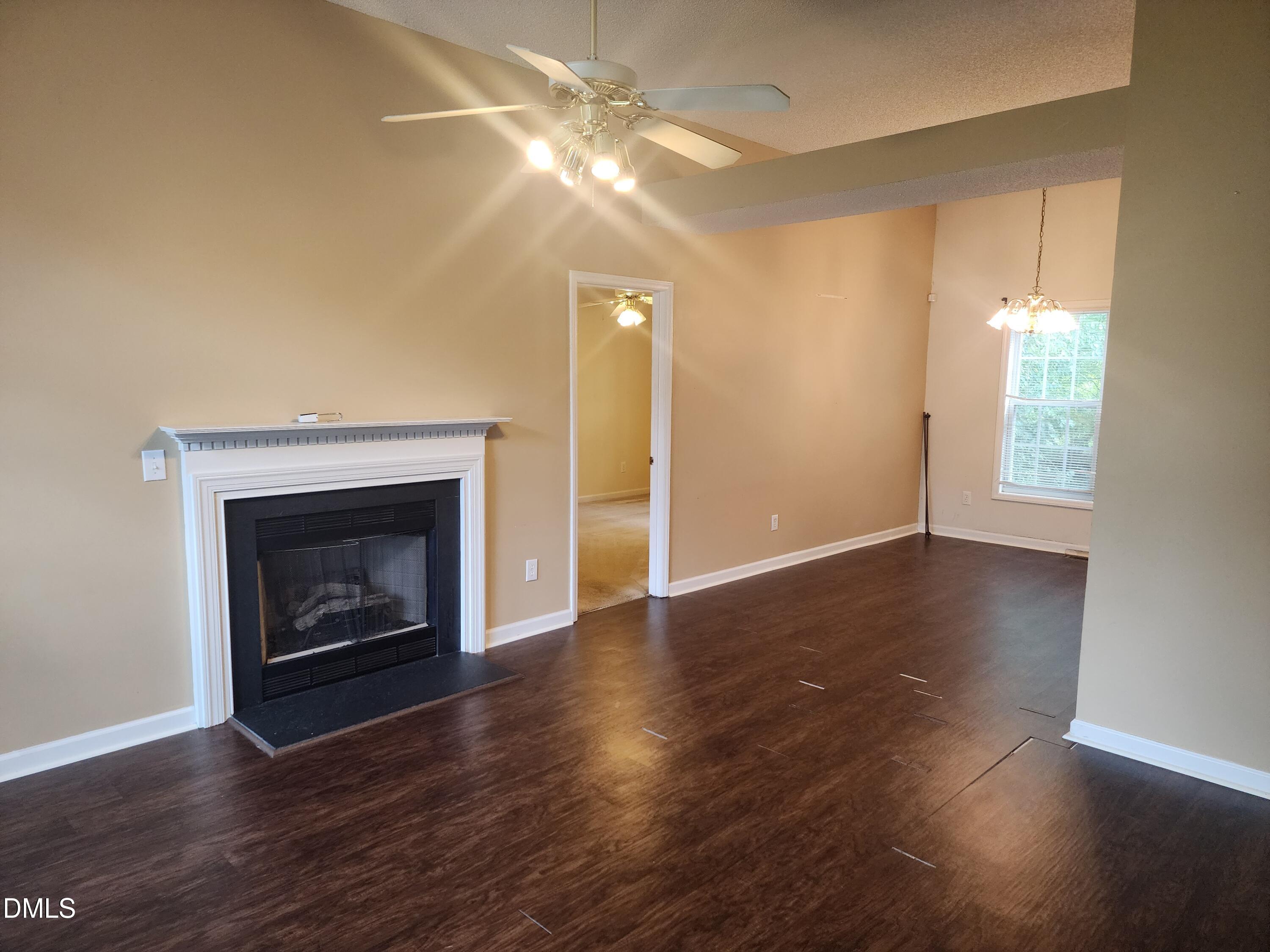 518 Johnson Street Garner, NC 27529 - Photo 3 of 17 an empty room with wooden floor fireplace and windows